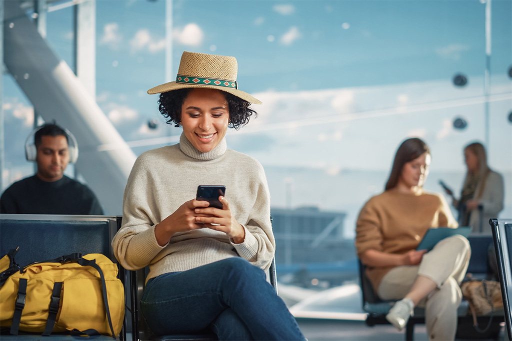 An image of a young woman looking at content on a mobile device in an airport.